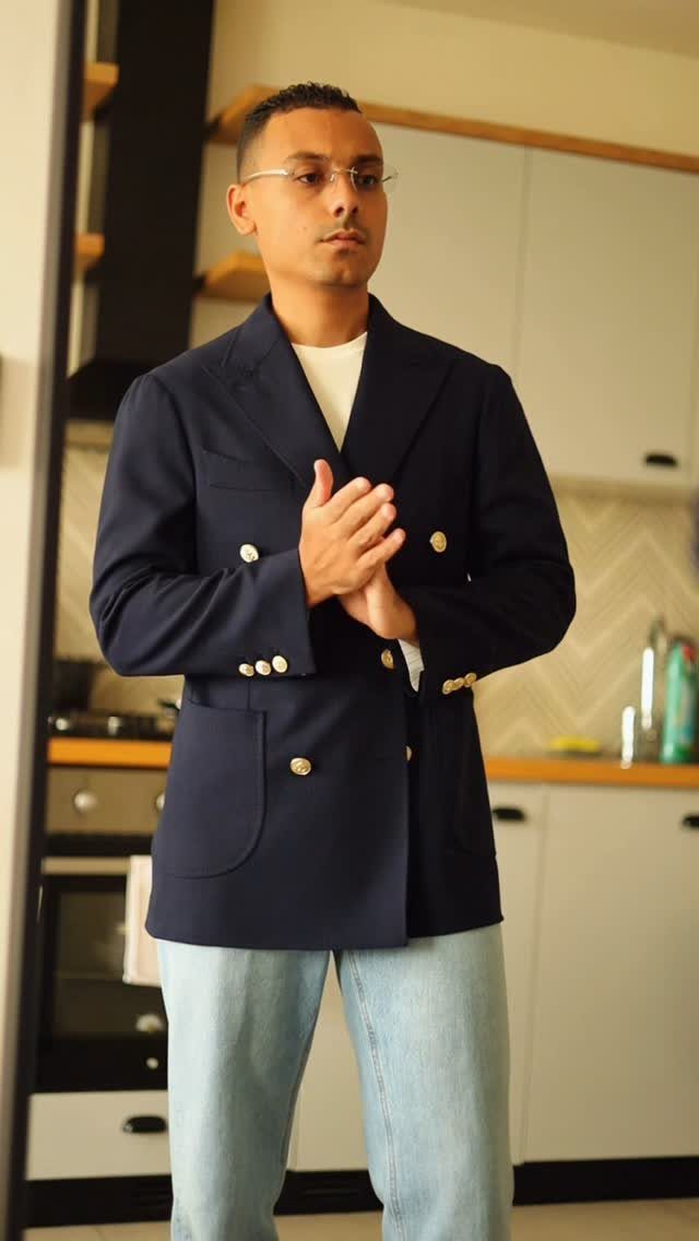 Man wearing a navy blue double-breasted blazer and light blue denim jeans.