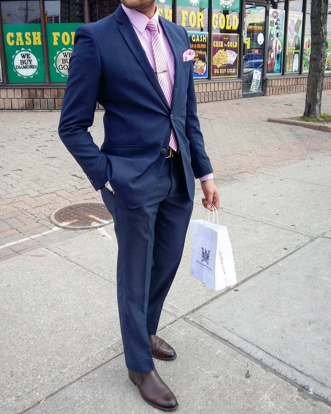 Man in a navy blue suit wearing a pink striped shirt and matching pink tie.