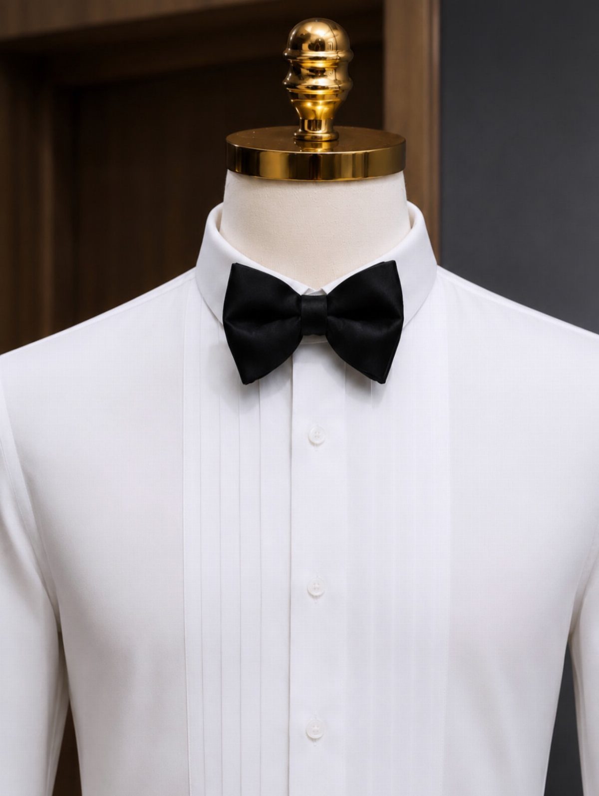 White pleated tuxedo shirt with a black bow tie on a mannequin.