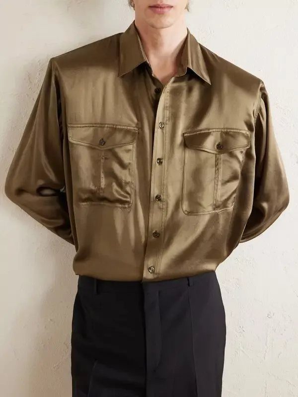Olive green satin button-down shirt with chest pockets worn by a person.