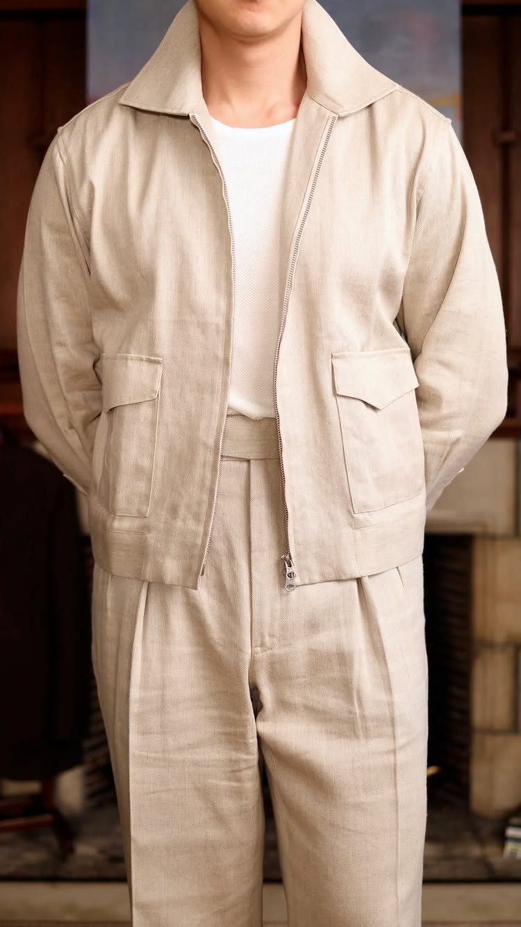 A person wearing a beige linen jacket and matching trousers over a white t-shirt.