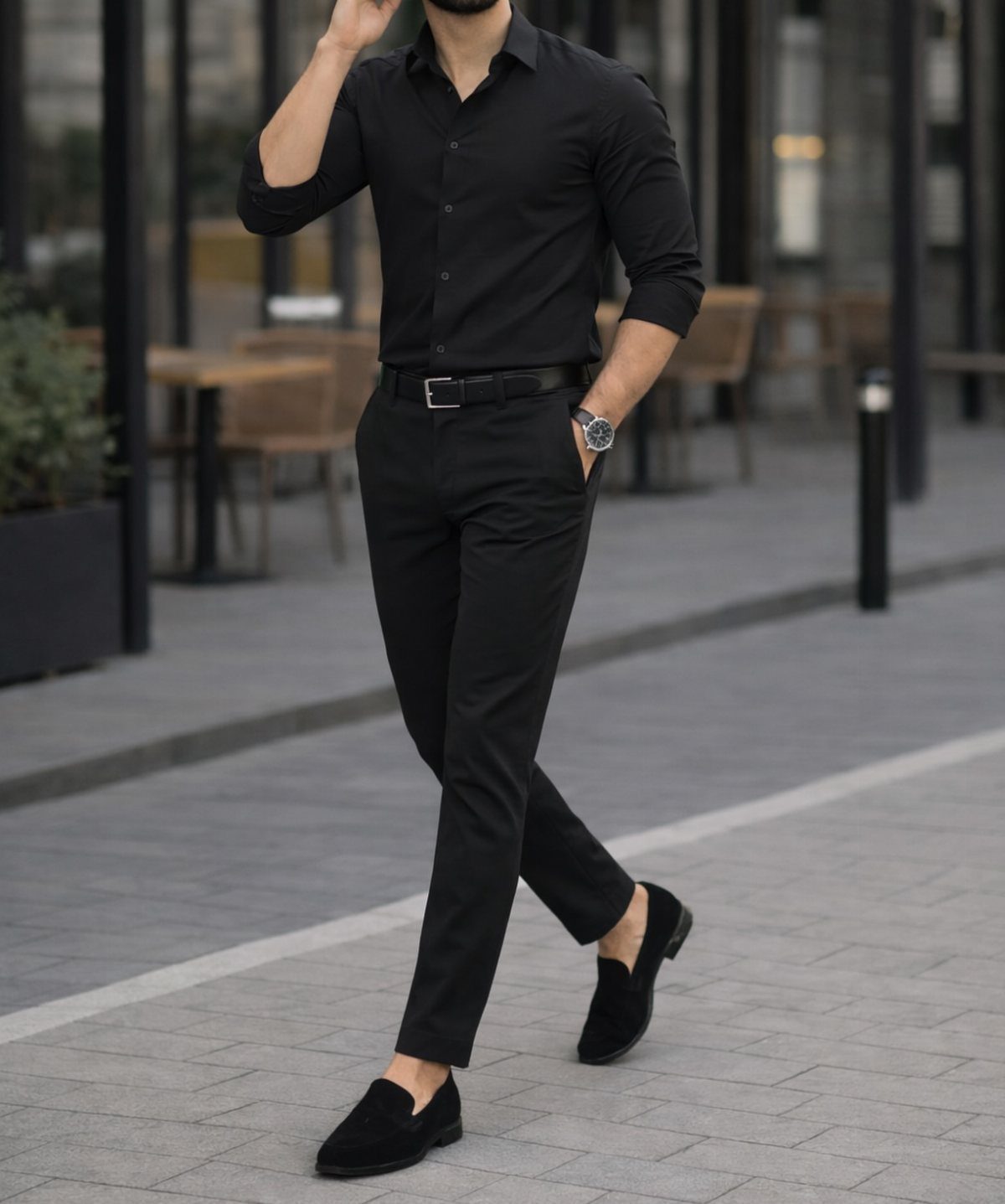 Man walking in an all-black outfit consisting of a button-down shirt, trousers, and loafers.