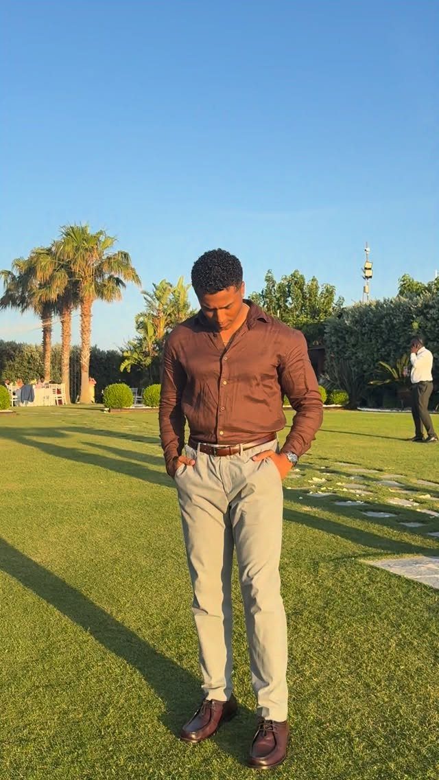 Man in brown shirt and grey chinos wearing a brown leather belt and matching shoes.