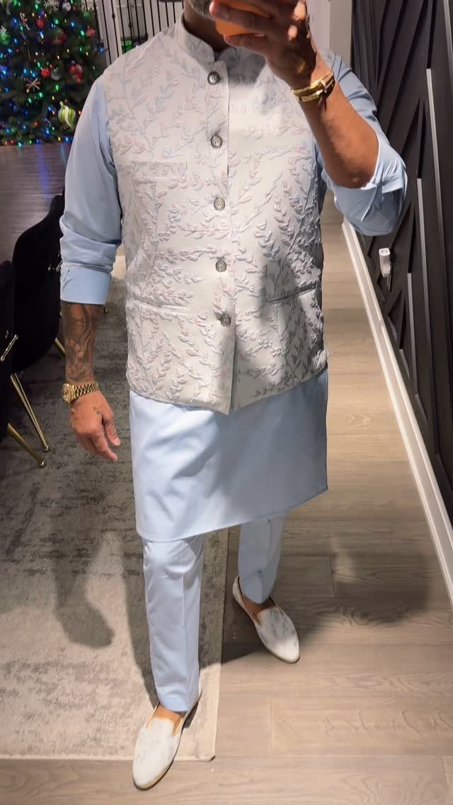 Man wearing a light blue tunic, matching trousers, and a grey patterned vest.