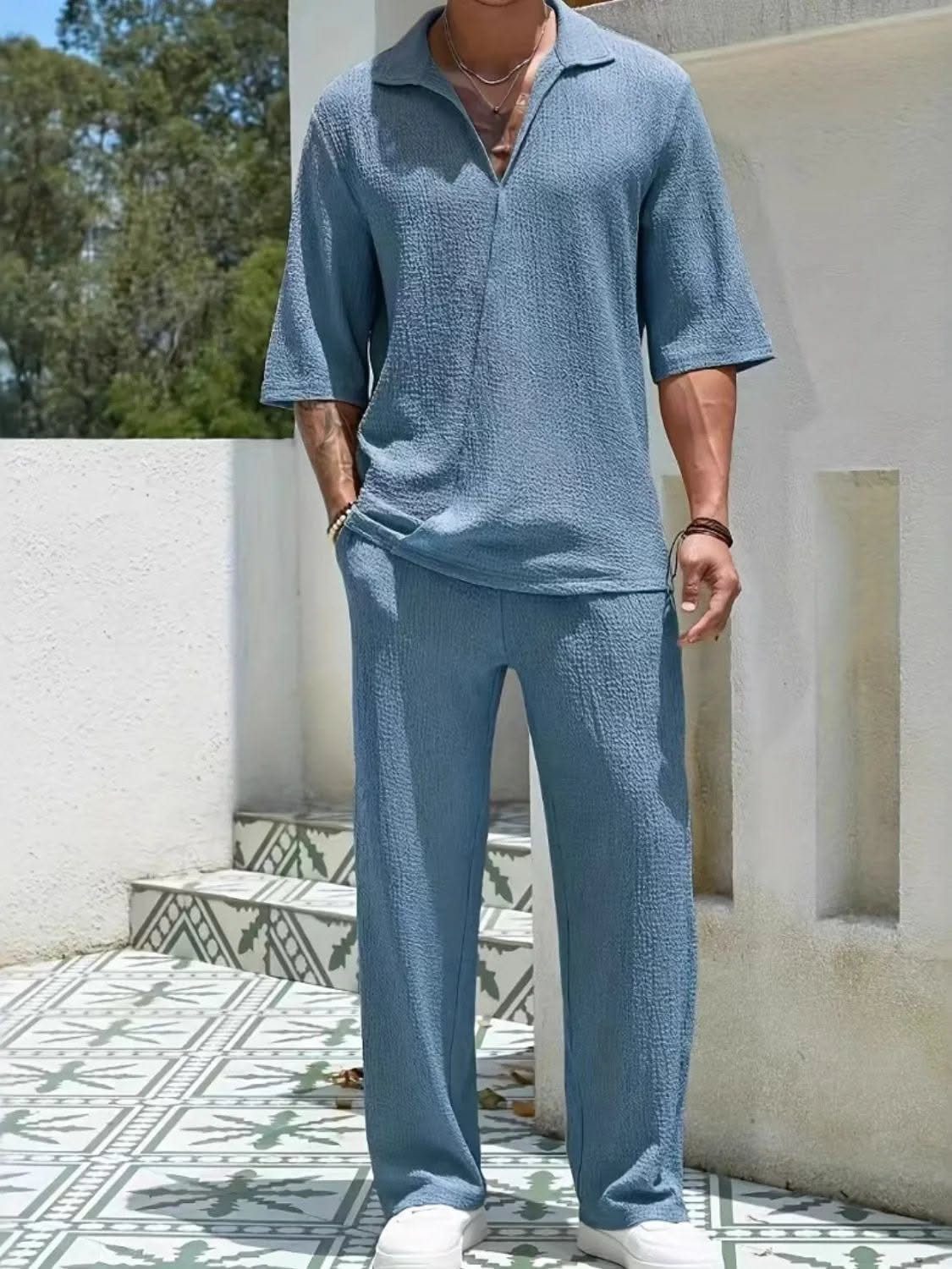 A man wearing a matching light blue textured short-sleeved shirt and trousers set.