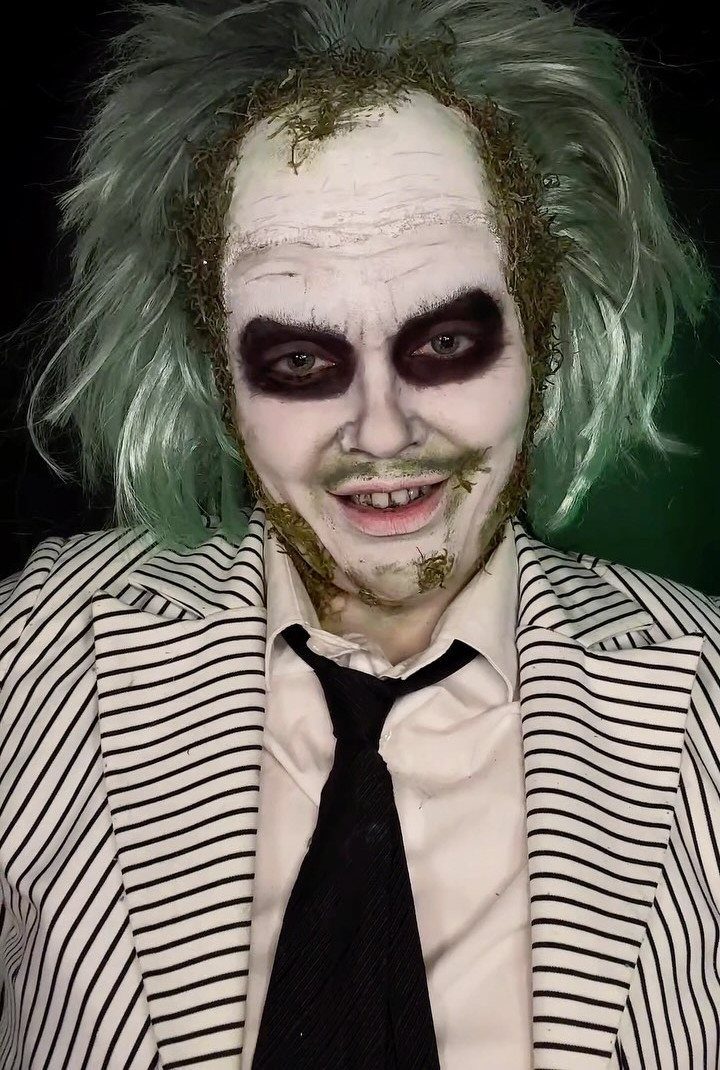 Man in Beetlejuice costume with green hair, white face paint, and a black and white striped suit.