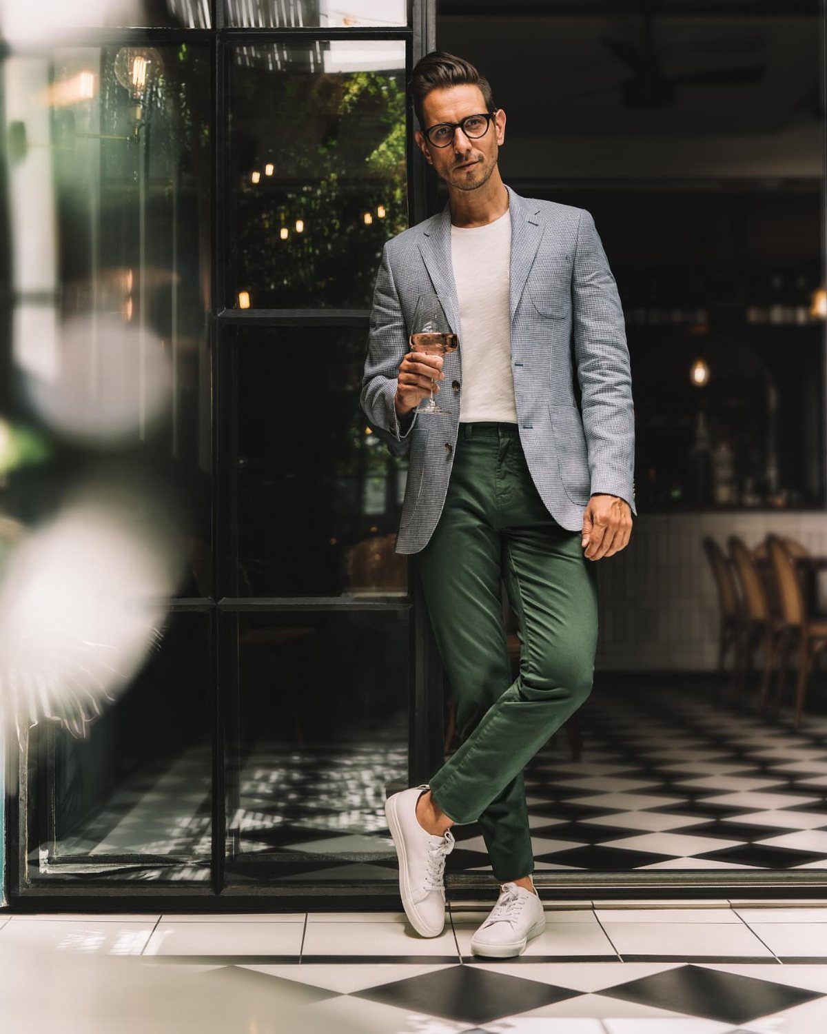 A man in a blue blazer, white t-shirt, and green chinos posing outdoors.