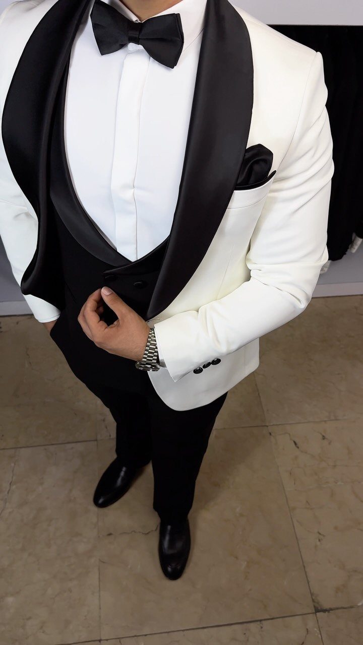 Man wearing a white tuxedo jacket with black lapels, black bow tie, and black trousers.