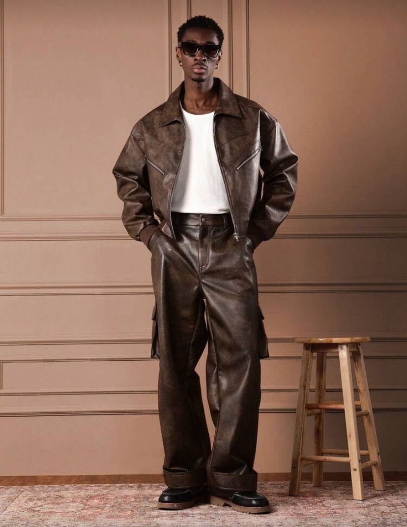 Man posing in a dark brown leather jacket, white t-shirt, and matching leather trousers.