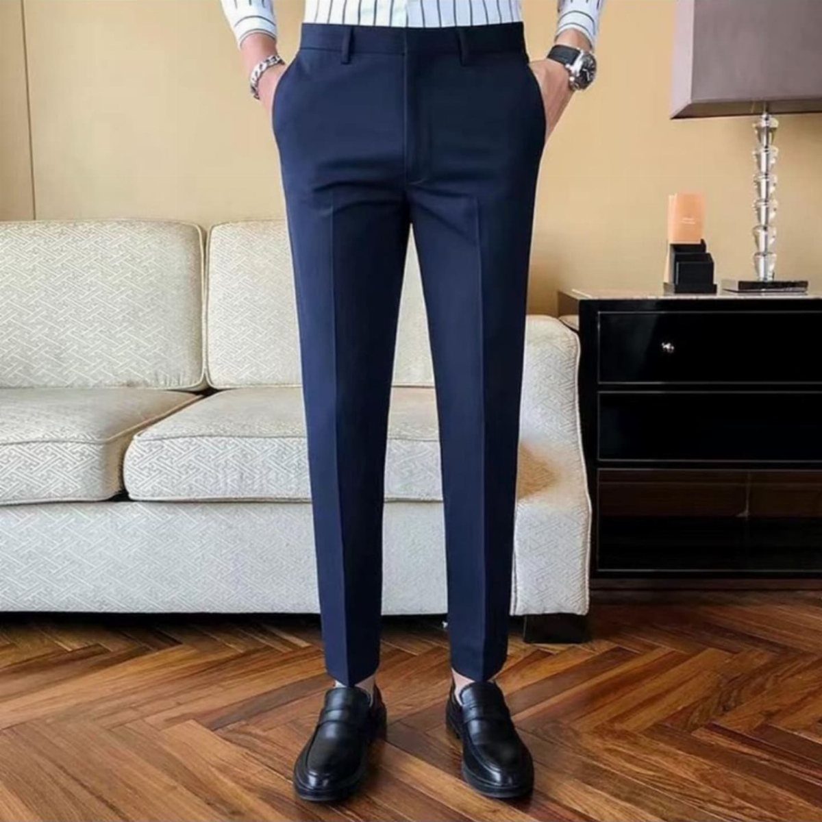 Man wearing navy blue tailored trousers and black leather shoes standing in a living room.