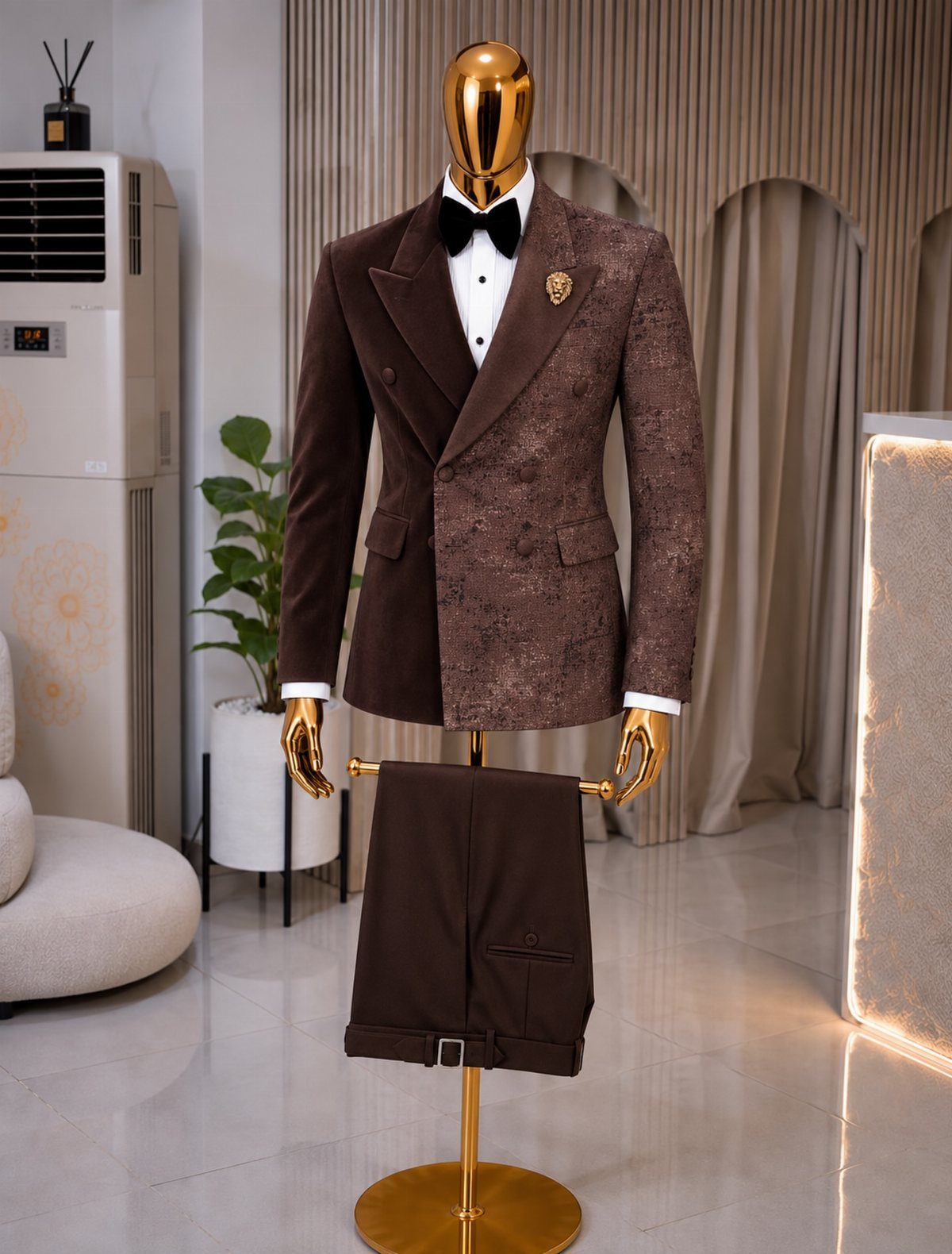A brown patterned double-breasted suit and matching trousers displayed on a gold mannequin.