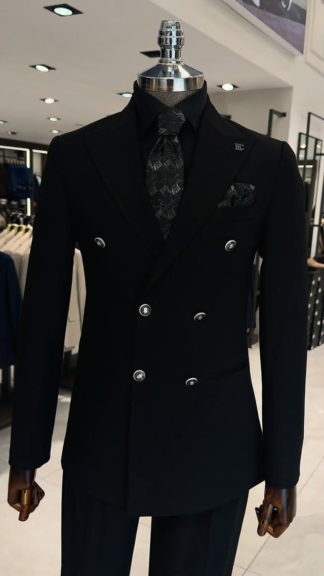 A black double-breasted suit jacket with a patterned tie displayed on a mannequin.