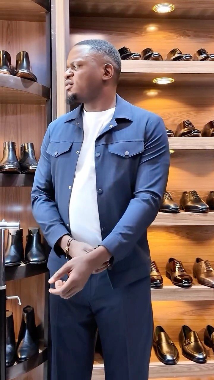 Man in a navy blue lightweight jacket and white t-shirt standing in a shoe store.