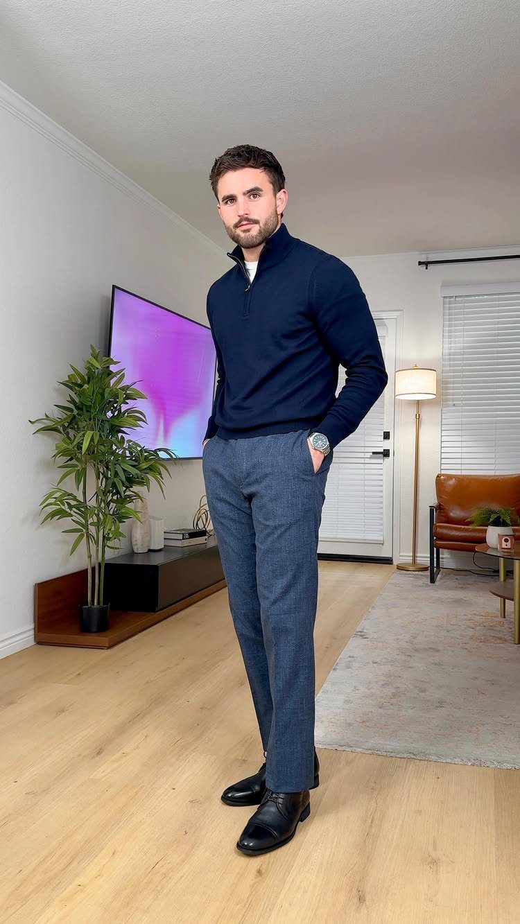 Man posing in a navy quarter-zip sweater, grey trousers, and black dress shoes.