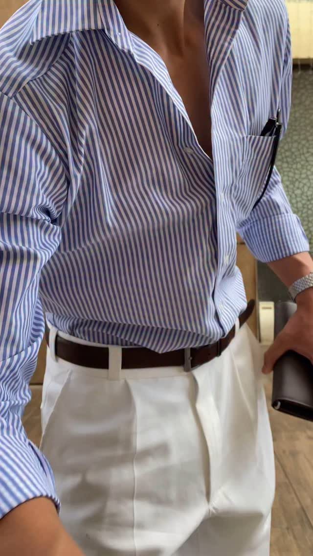 Man wearing a blue striped shirt, white trousers, and a brown leather belt.