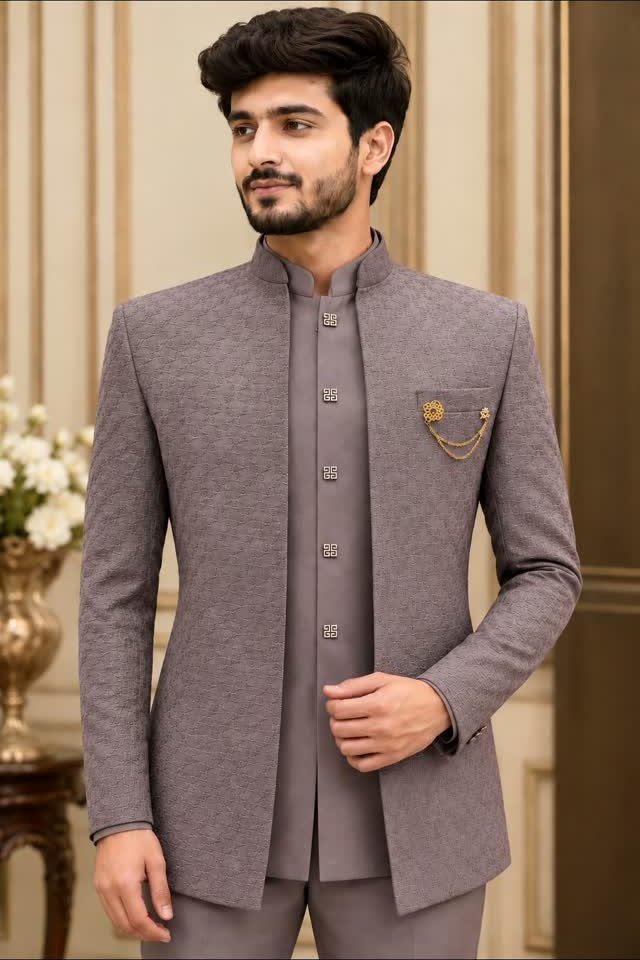 A man posing in a grey textured Nehru jacket with a gold chain brooch.