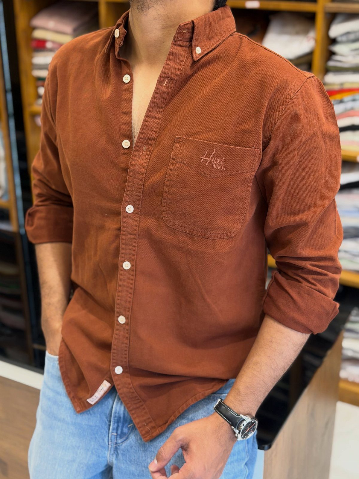 Man wearing a rust-colored corduroy button-up shirt and light blue denim jeans.