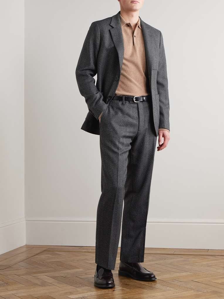 Man wearing a charcoal grey suit over a tan polo shirt and black leather shoes.