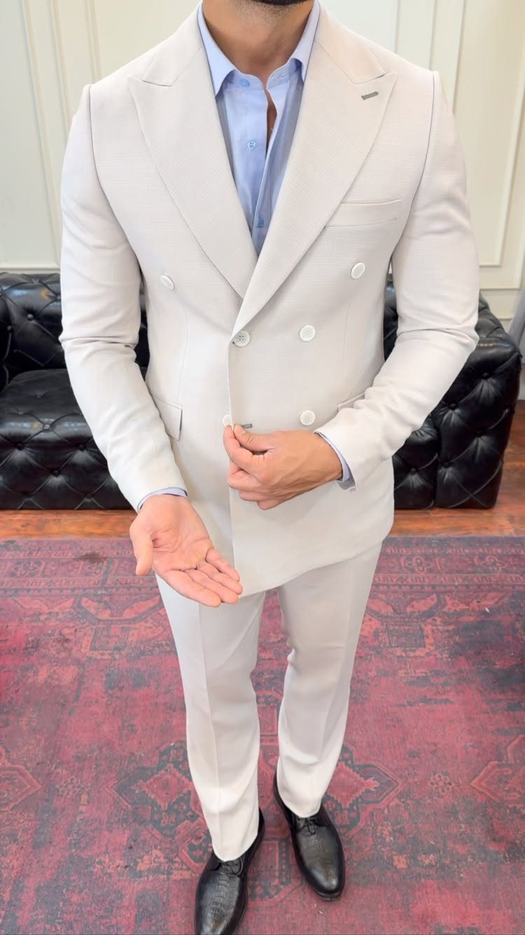 Man wearing a light beige double-breasted suit and light blue open-collar shirt.