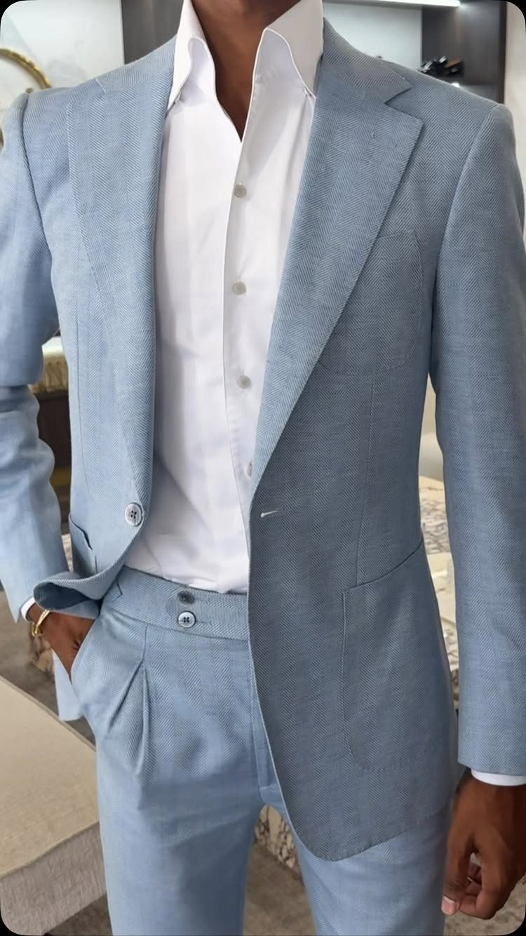 Man wearing a light blue suit with an unbuttoned white dress shirt.