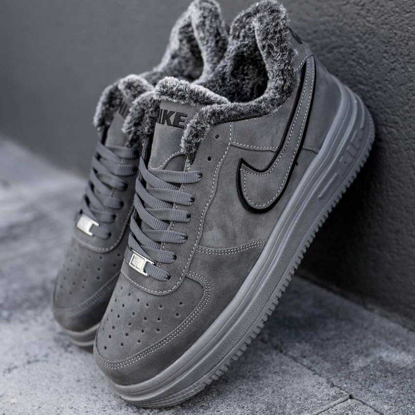 Grey suede Nike sneakers with thick grey faux fur lining resting on concrete.